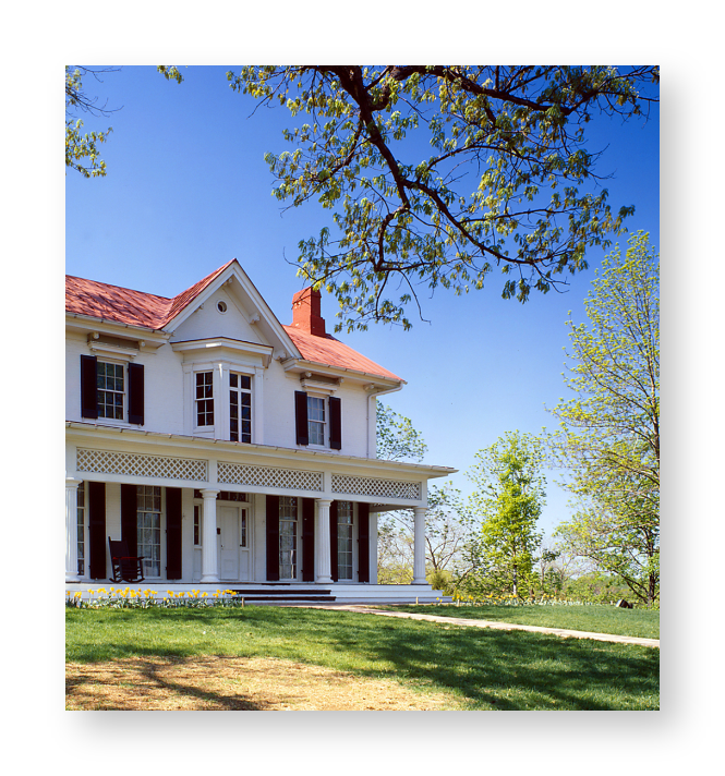 A white house with a tree and green grass